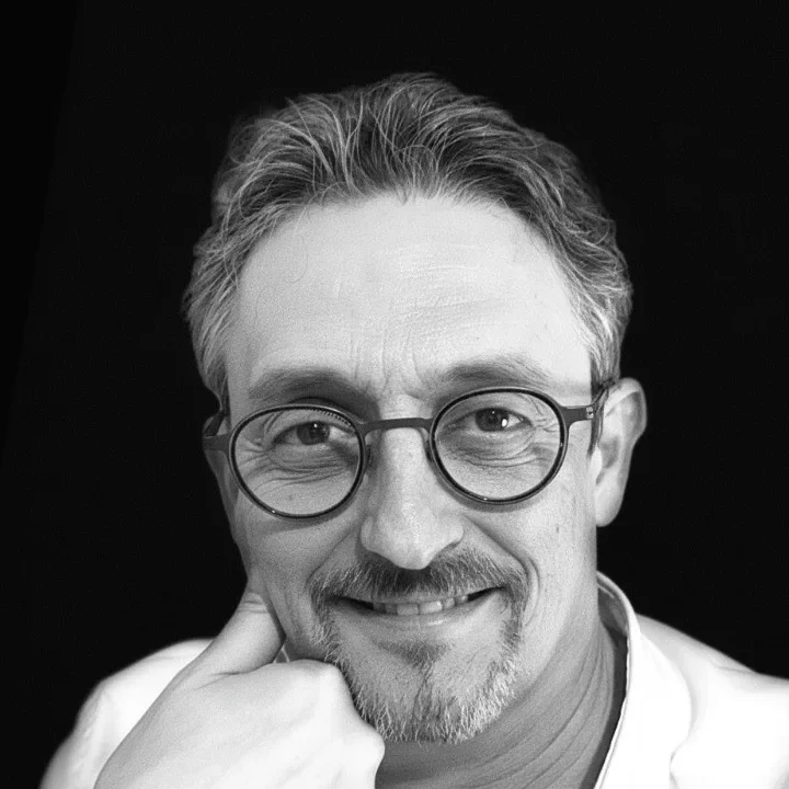 Portrait de Bruno Bacile, souriant, la main sous le menton